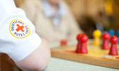 Foto: Arm einer Pflegerin vor einem Brettspiel